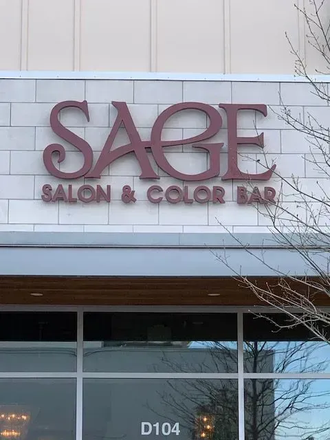 Sage Salon & Color Bar sign in maroon lettering over a store front.
